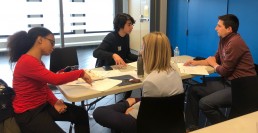 2 students and 2 adults at a table doing mock job interviews