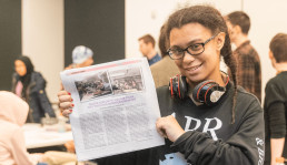 image of student holding the TiP newspaper
