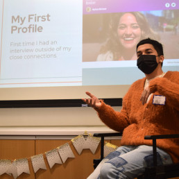 seated student presenting in front of a powerpoint
