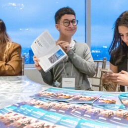 Smiling student holds up a booklet, held open to their piece of writing