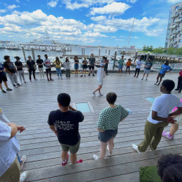 students standing in a circle at the ica with ocean in the background