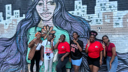 group smiling in front of mural