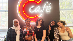 students smiling in front of neon sign
